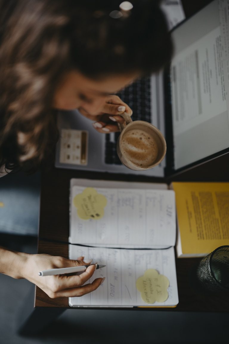 The Two-Word Trick That Doubles Follow-Through: If-Then Young person writes notes in planner while drinking coffee from above